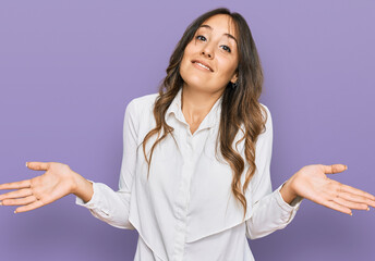 Young brunette woman wearing casual clothes clueless and confused expression with arms and hands...