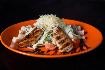 oriental salad with chicken on an orange plate, beautiful serving, dark background