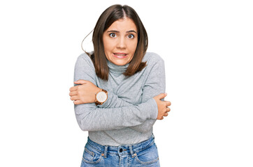 Young beautiful woman wearing casual turtleneck sweater shaking and freezing for winter cold with...