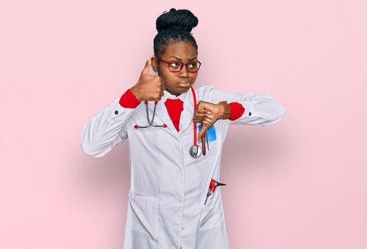 Young african american woman wearing doctor uniform and stethoscope doing thumbs up and down, disagreement and agreement expression. crazy conflict