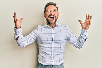 Fototapeta premium Middle age man wearing business clothes crazy and mad shouting and yelling with aggressive expression and arms raised. frustration concept.
