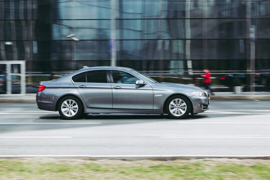 BMW 5 Series F10 vehicle on the city road. Fast moving silver sedan car on Moscow streets. Accelerating with low-emission. Compliance with speed limits on the road