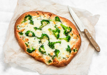 Vegetarian broccoli mozzarella cheese pizza on a light background, top view