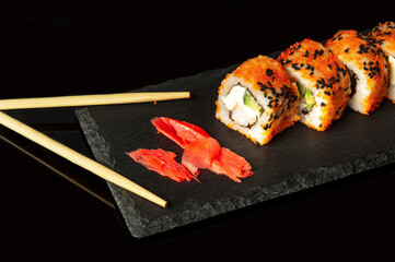 Traditional sushi and chopsticks. Philadelphia with salmon, avocado and cheese. Japanese cuisine on black background