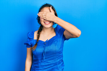 Young hispanic girl wearing casual clothes smiling and laughing with hand on face covering eyes for surprise. blind concept.