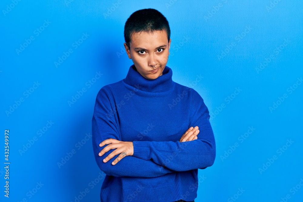 Wall mural Beautiful hispanic woman with short hair wearing turtleneck sweater skeptic and nervous, disapproving expression on face with crossed arms. negative person.