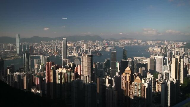 Famous view from Victoria Peak: skyscrapers of the financial and business district and airplane crossing the sky. Hong Kong Island, Kowloon Peninsula, ICC, Sky100