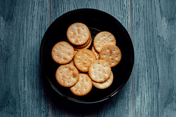 Salty biscuit cracker on black plate on wooden table background