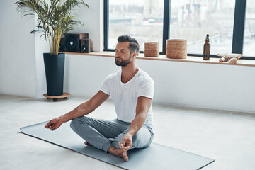 Totally relaxed young man doing yoga while sitting 