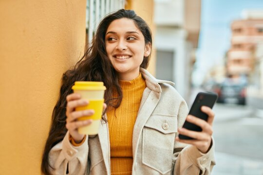 Young middle east woman using smartphone drinking coffee at the city.