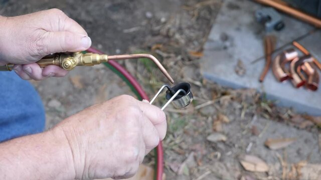 Maintenance worker using an acetylene torch to weld a pipe