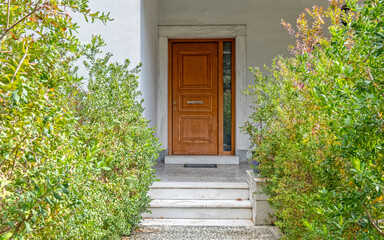 Fototapeta na wymiar corridor between green plants to elegant house wooden door, Athens Greece
