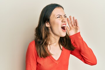 Young brunette woman wearing casual clothes shouting and screaming loud to side with hand on mouth. communication concept.