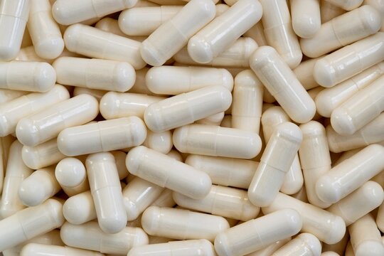 White vitamin supplement capsules scattered loosely, flat lay background format.