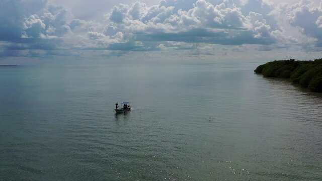 Aerial Panning Shot Of People On Boat In Sea Against Cloudy Sky, Drone Flying Over Ocean - Punta Allen, Mexico