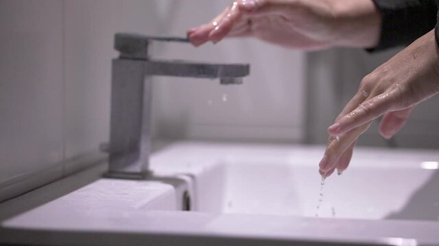 Person shutting water faucet, finishing washing hands, saving conserving water
