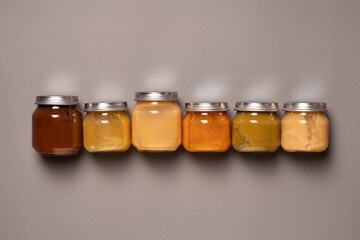 Glass jars with mashed on grey background. Baby puree. First baby food concept.