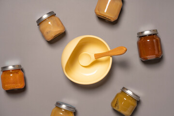 Silicone bowl, spoon and jars with baby food. First baby food concept. Flat lay