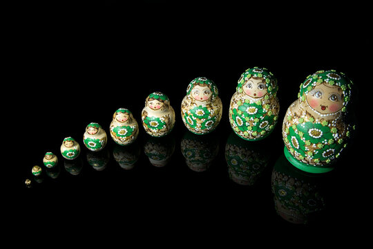 russische Matrjoschka Figuren in einer Reihe spiegeln sich auf schwarzem Hintergrund