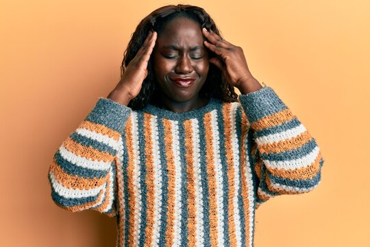 African young woman wearing wool winter sweater suffering from headache desperate and stressed because pain and migraine. hands on head.