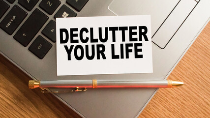A notebook with text DECLUTTER YOUR LIFE on the office desk, a laptop with stationery. A blank notepad for entering a copy or text. business