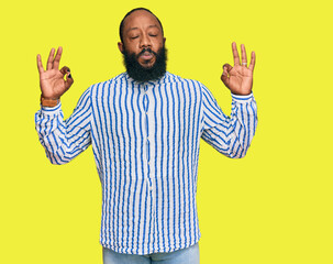 Fototapeta premium Young african american man wearing business shirt relax and smiling with eyes closed doing meditation gesture with fingers. yoga concept.