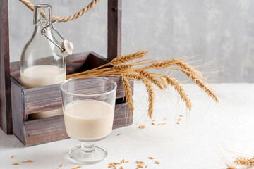 Gluten free oat milk in a glass bottle and glass on a light background. Organic natural vegetarian drink without gluten and lactose in a wooden box. Health concept.