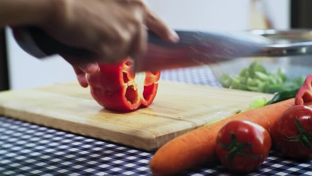  Close up housewife hand slice Sweet pepper  or bell papper by knife for cooking in Kitchen