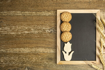Chalk board, wheat cookies, wheat ears over rustic background with copy space. Harvest, Shavuot concept.