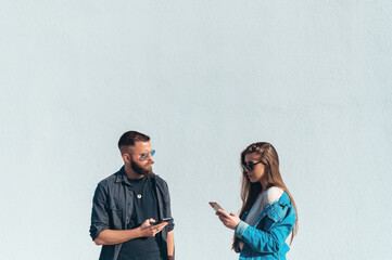 Young beautiful couple using smartphones outside