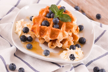 Waffles with blueberries and whipped cream.