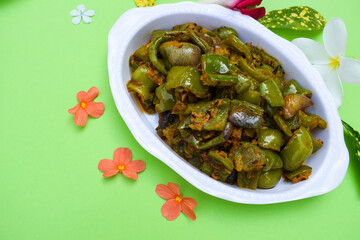 Delicious Capsicum or green bellpepper curry. Stir fried with onions sauted Indian asian sabji with masala. On red background food image copyspace to write text. decorated shimla mirch sabzi