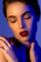 Beautiful young woman with clean perfect skin in colored neon lights. 