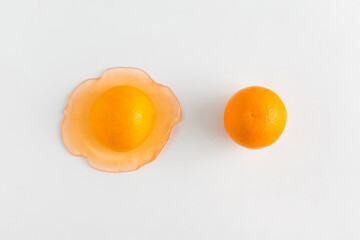 Creative summer idea with a whole and a slice of orange melting on a white background. Healthy diet or nature concept. Organic tropical fruit juice. Flat lay.
