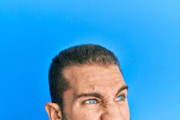 Young caucasian man showing head and half face angry and mad screaming frustrated and furious, shouting with anger. rage and aggressive concept.