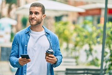 Young caucasian man using smartphone drinking coffee at the city.