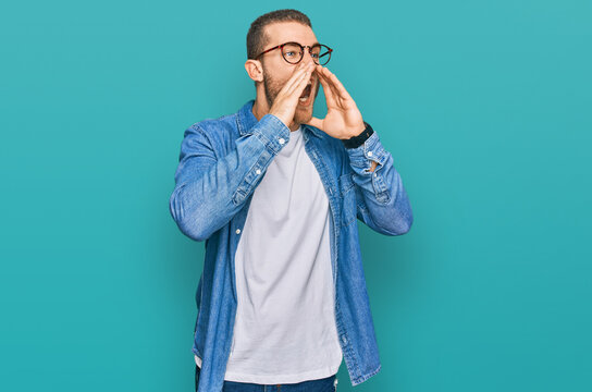 Young caucasian man wearing casual clothes shouting angry out loud with hands over mouth