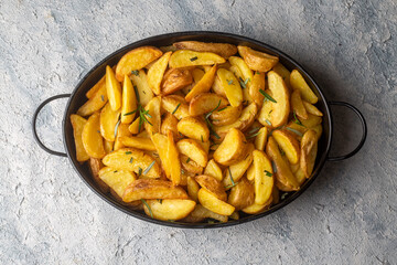 Roasted potato wedges with herbs and sea salt on plate, top view (Turkish name; elma dilim patates)