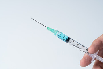 Closeup of a hand with a syringe on a white background