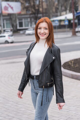 Fototapeta premium Portrait of a beautiful and positive redhead woman with clothes in grunge style. Posing while walking