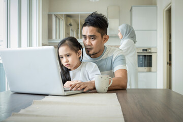 Fototapeta premium father or husband working from home while child is sitting on his lap