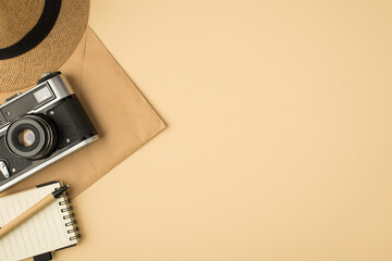 Top view photo of hat pen on notebook and camera on craft paper envelope on isolated beige background with copyspace