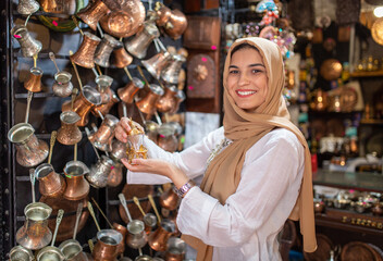 Portrait of Arabian Muslim woman with hijab buying handmade pottery.