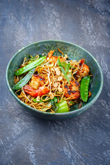 Modern style traditional Thai phak kung curry with barbecue king prawns and noodles as close-up in Nordic design bowl with copy space