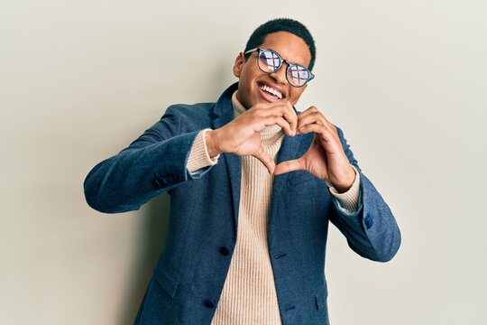 Young handsome hispanic man wearing elegant clothes and glasses smiling in love doing heart symbol shape with hands. romantic concept.