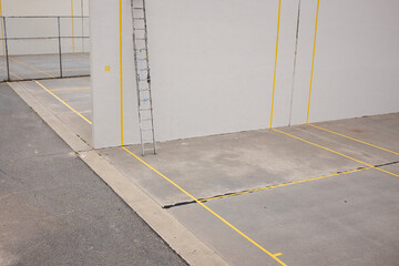 Grey concrete outdoor squash court with yellow lines