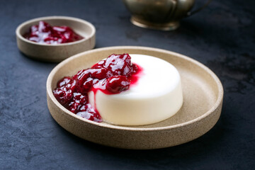 Modern style traditional blancmange almond pudding with sour cherry coulis served as close-up in a...