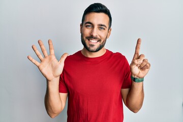 Young hispanic man wearing casual clothes showing and pointing up with fingers number six while smiling confident and happy.