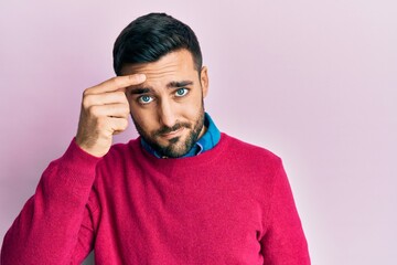 Young hispanic man wearing casual clothes pointing unhappy to pimple on forehead, ugly infection of...