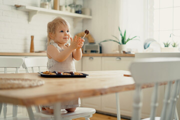 An interesting activity for the baby. A child is playing in the kitchen with cake pans. Happy children's mood. The cook girl eats pastries cookies, dessert confectionery.